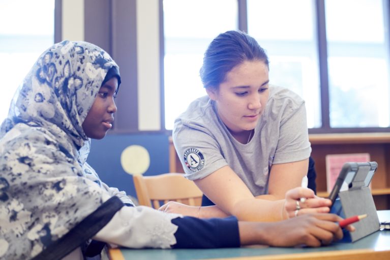 Student and AmeriCorps member work on laptop together